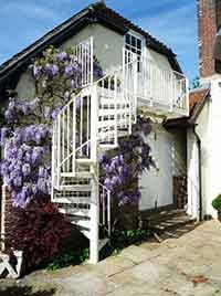 outdoor setting with white spiral and balcony with purple flowers and blue sky