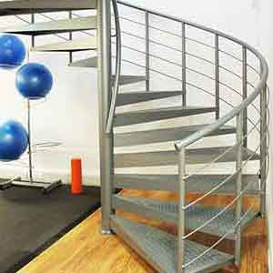 Steel spiral stair in grey with exercise equipment behind