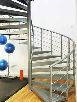 exercise mat and blue exercise balls to left and grey spiral stair to right