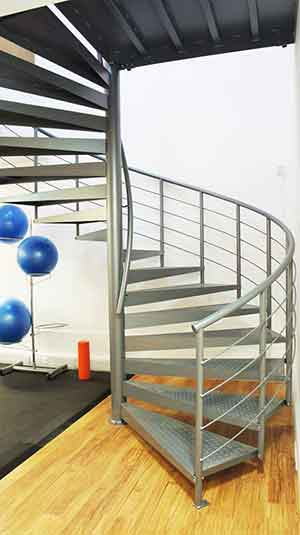 exercise mat and blue exercise balls to left and grey spiral stair to right