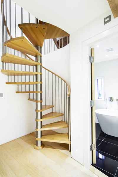 Wooden Spiral Staircase with stainless steel spindles and white walls behind