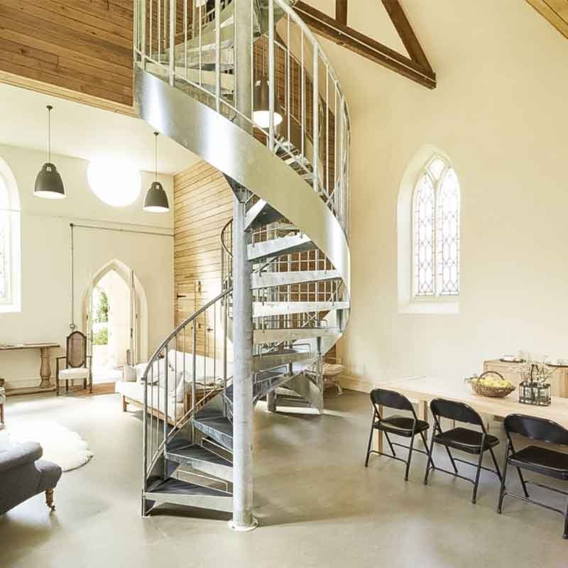 large grey steel spiral staircase with concrete floor below