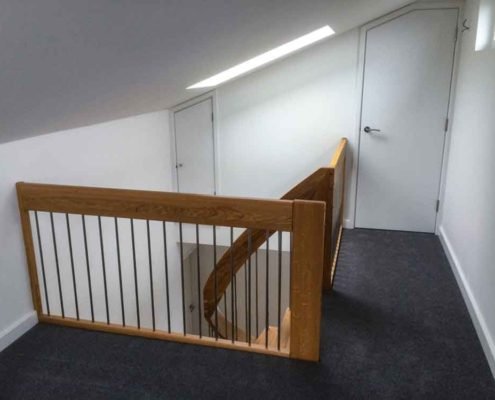 oak handrail around a stairwell with stainless spindles