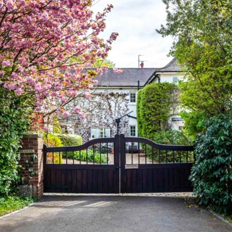 wooden gates in front of white house with trees