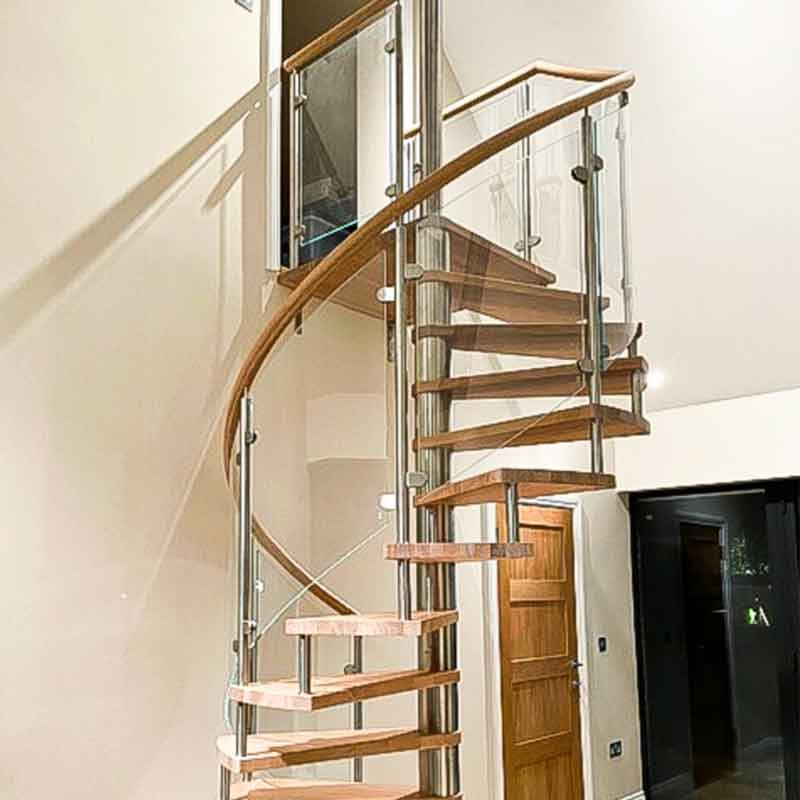 Glass sided spiral stair with wood handrail in house