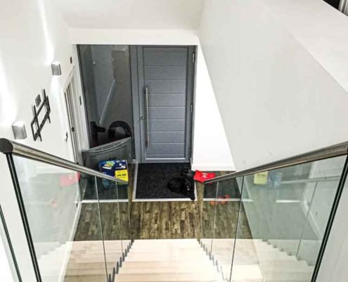 looking down a wood stair with glass panels