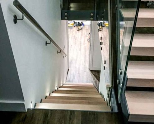 Looking down a wooden stair with wall handrail