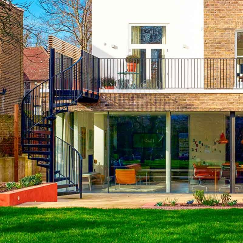 garden with black spiral stair leading upto balcony