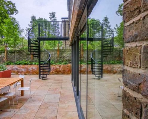 patio outside a house with a spiral stair leading to a walkway