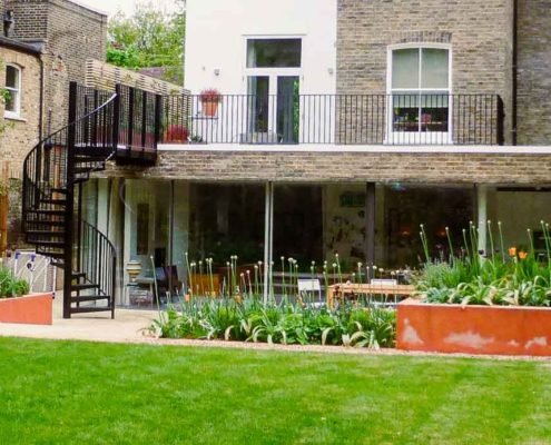 garden behind a grand house with grass and plants