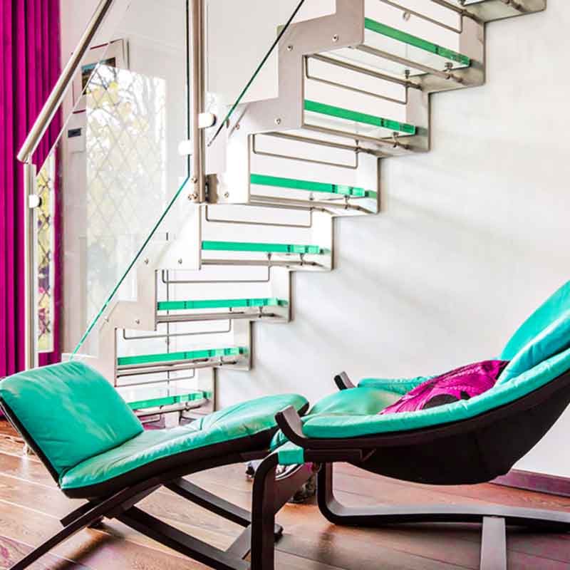 turquoise chaise beneath a glass staircase