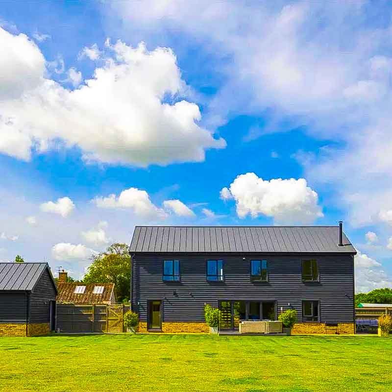 Brilliant-blue-sky-above-a-dark-grey-house-and-grass-in-foreground
