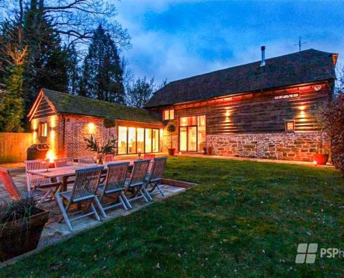 Glass-Staircase-Haywards-Heath-outdoor-table-with-converted-barn-behind