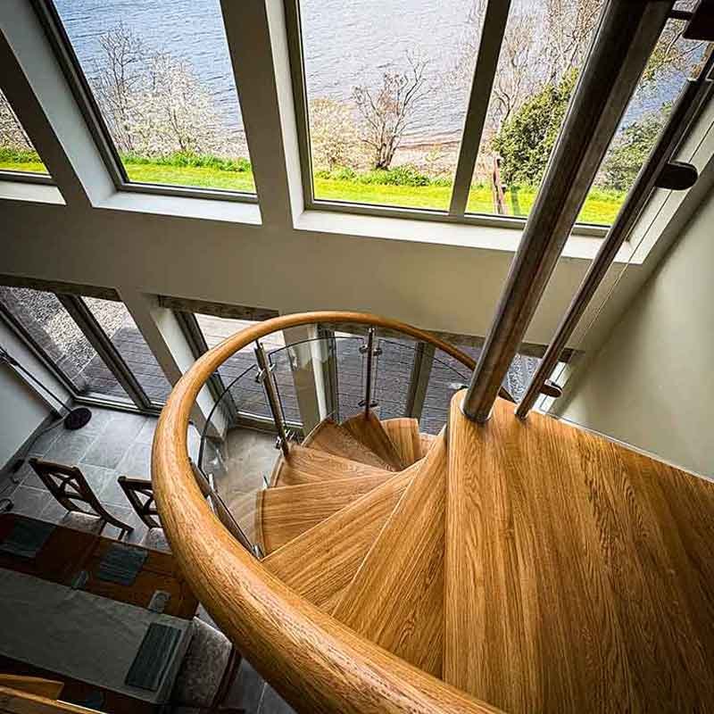 a wooden spiral twisting down in a house with large windows