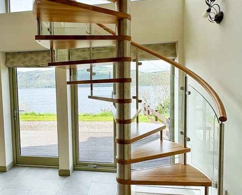 transprent spiral staircase with wooden steps and a window behind